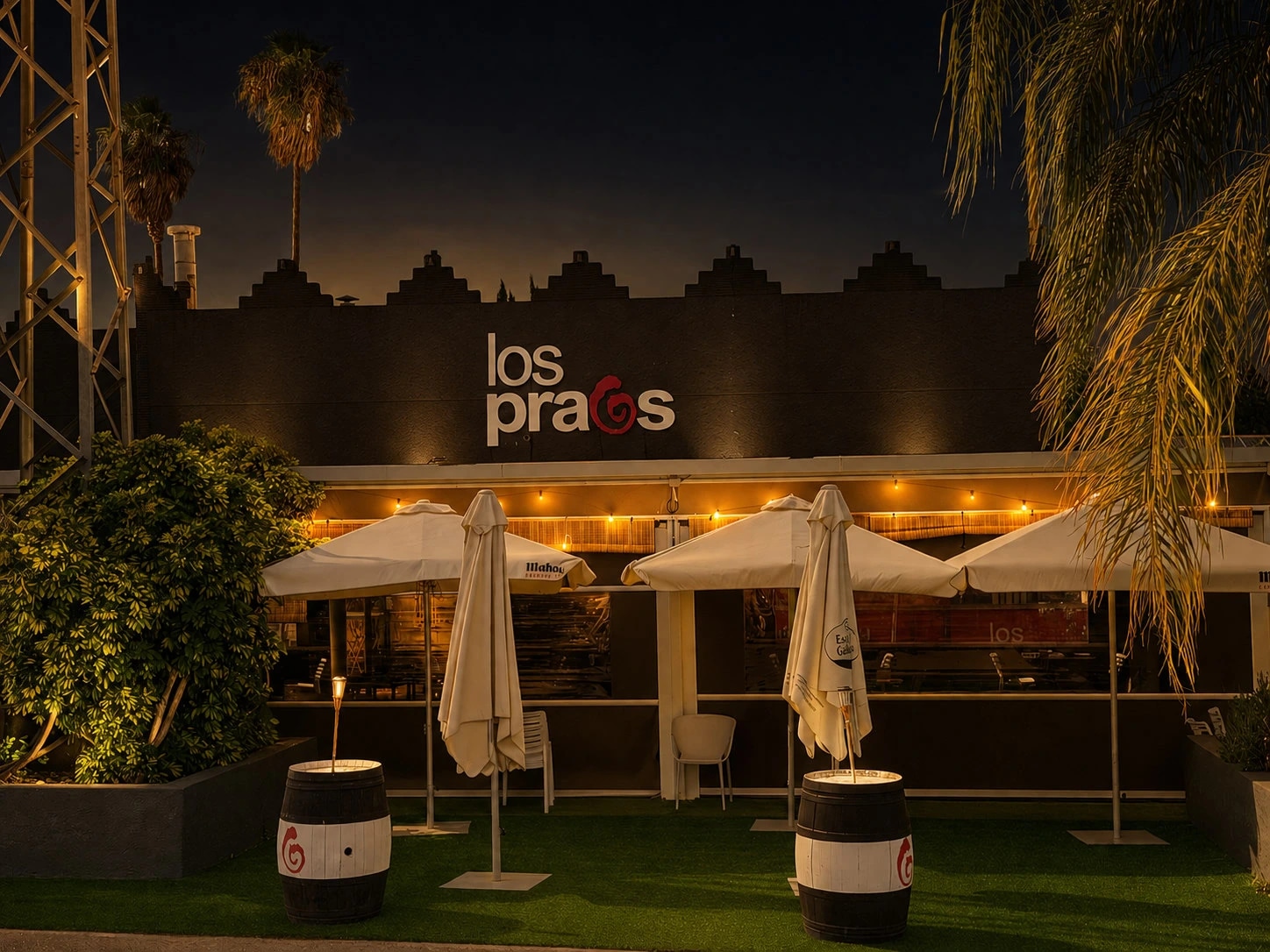 Fachada del restaurante Los Praos de noche, con el rótulo y las guirnaldas encendidas